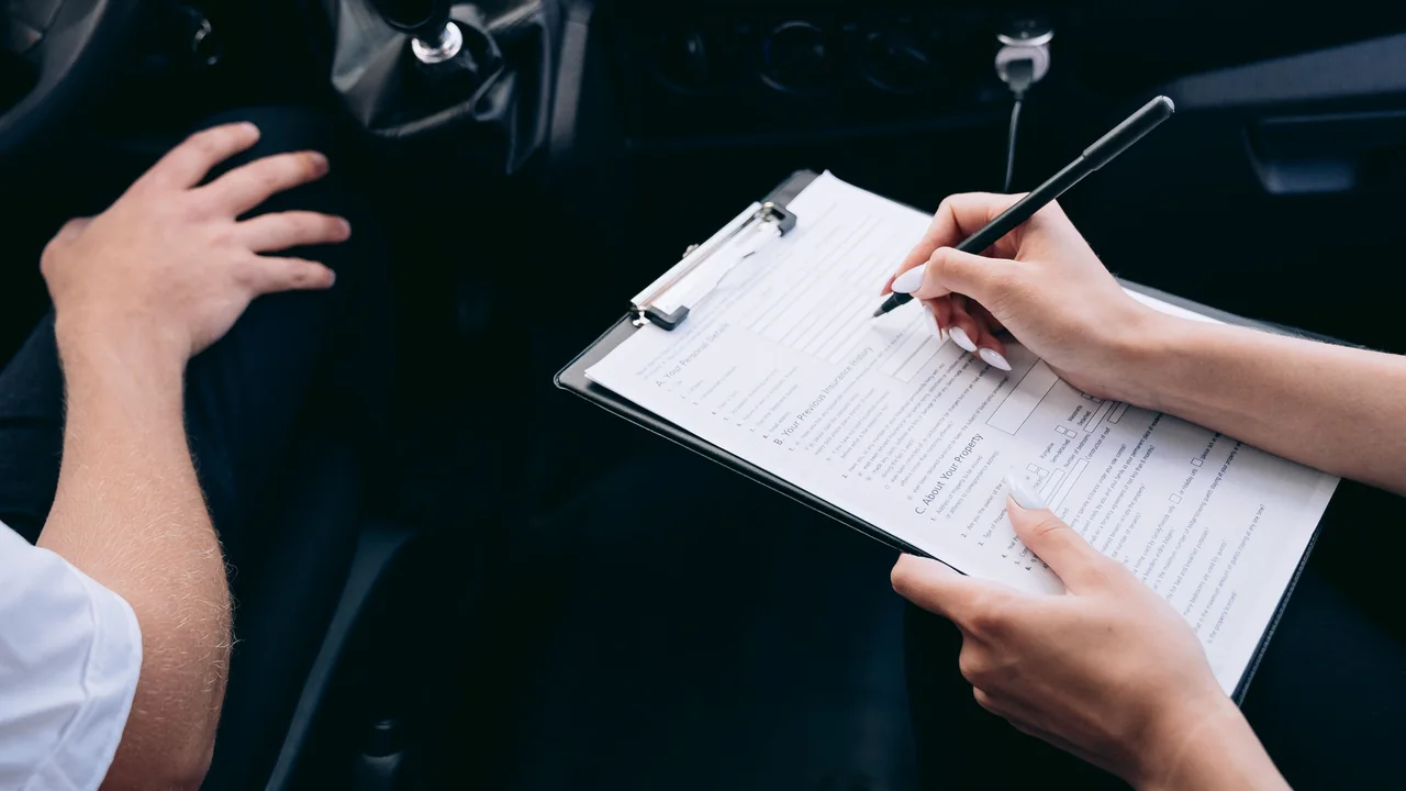 Pessoa preenchendo uma ficha em uma prancheta dentro de um carro.