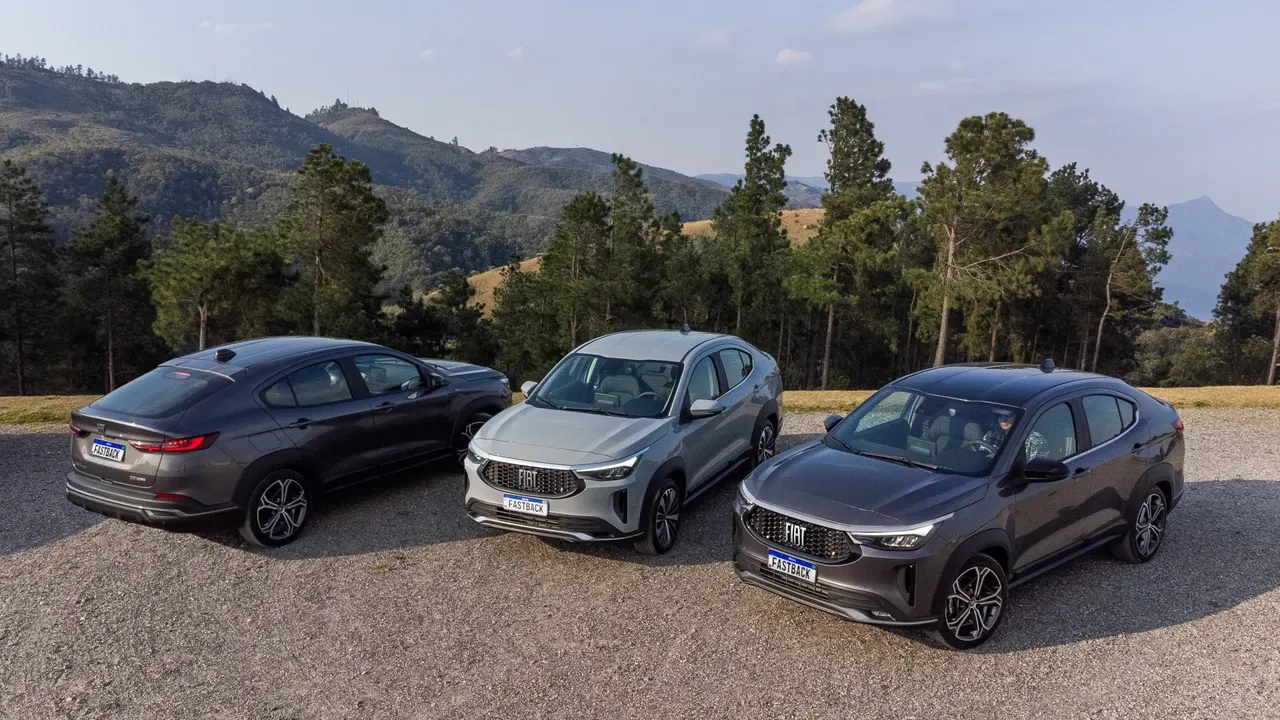 Três Fiat Fastback de cores diferentes estacionados ao ar livre.