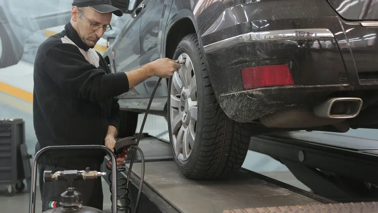 Mecânico verificando a pressão do pneu de um carro na oficina.