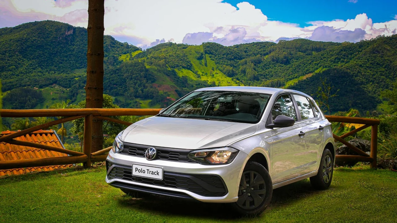 Volkswagen Polo Track prateado estacionado em um gramado, com montanhas ao fundo.