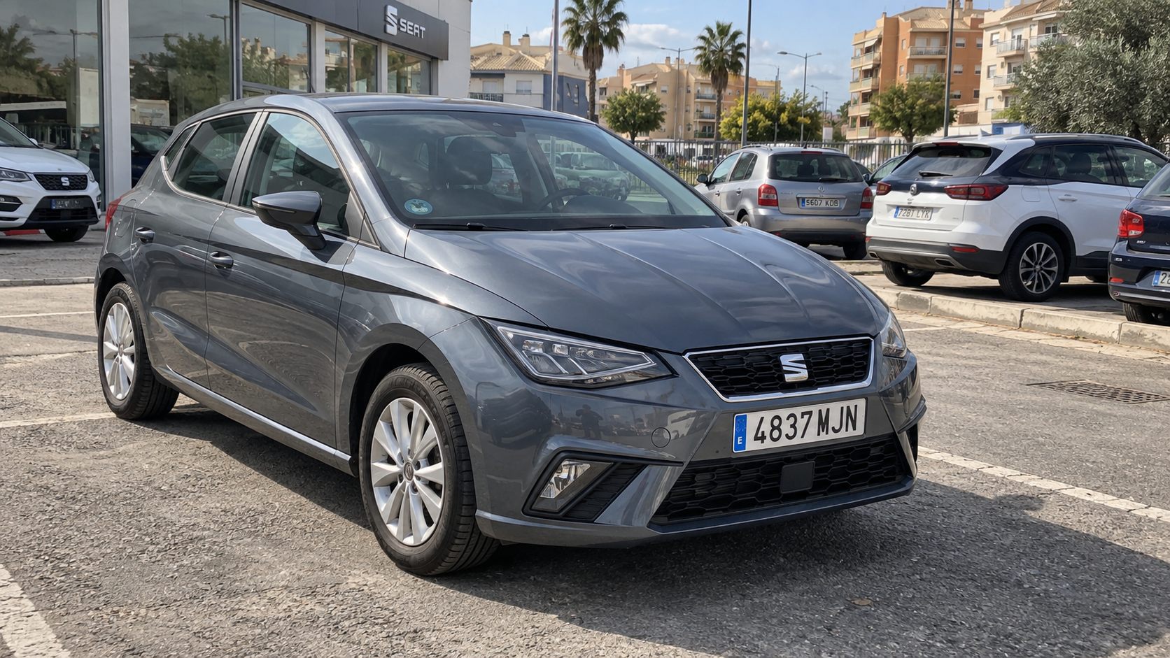 Ilustración editorial creada con IA: SEAT Ibiza gris en un aparcamiento de vehículos en España.